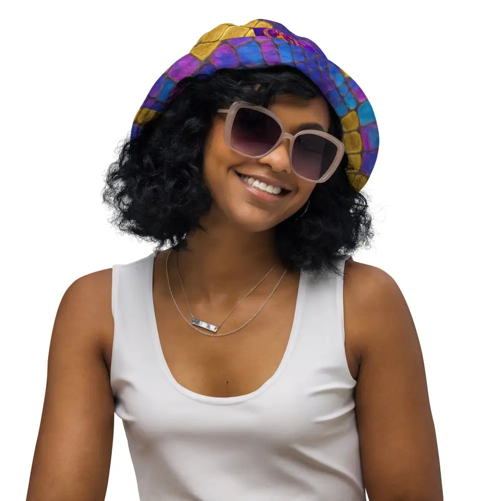 Frau trägt Bossbabe Bucket Hat mit buntem Snake-Print und Glitzerakzenten, kombiniert mit weißem Top und Sonnenbrille