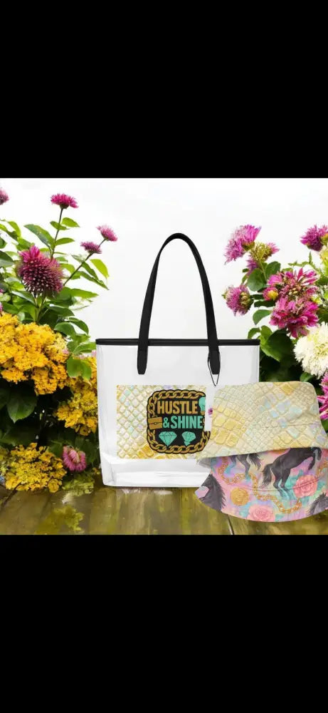 Transparente Tragetasche mit "Hustle & Shine" Design und schwarzen Griffen, umgeben von Blumen
